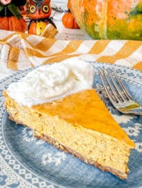 A slice of Pumpkin Cheesecake with Gingersnap Graham Cracker Crust on a plate.