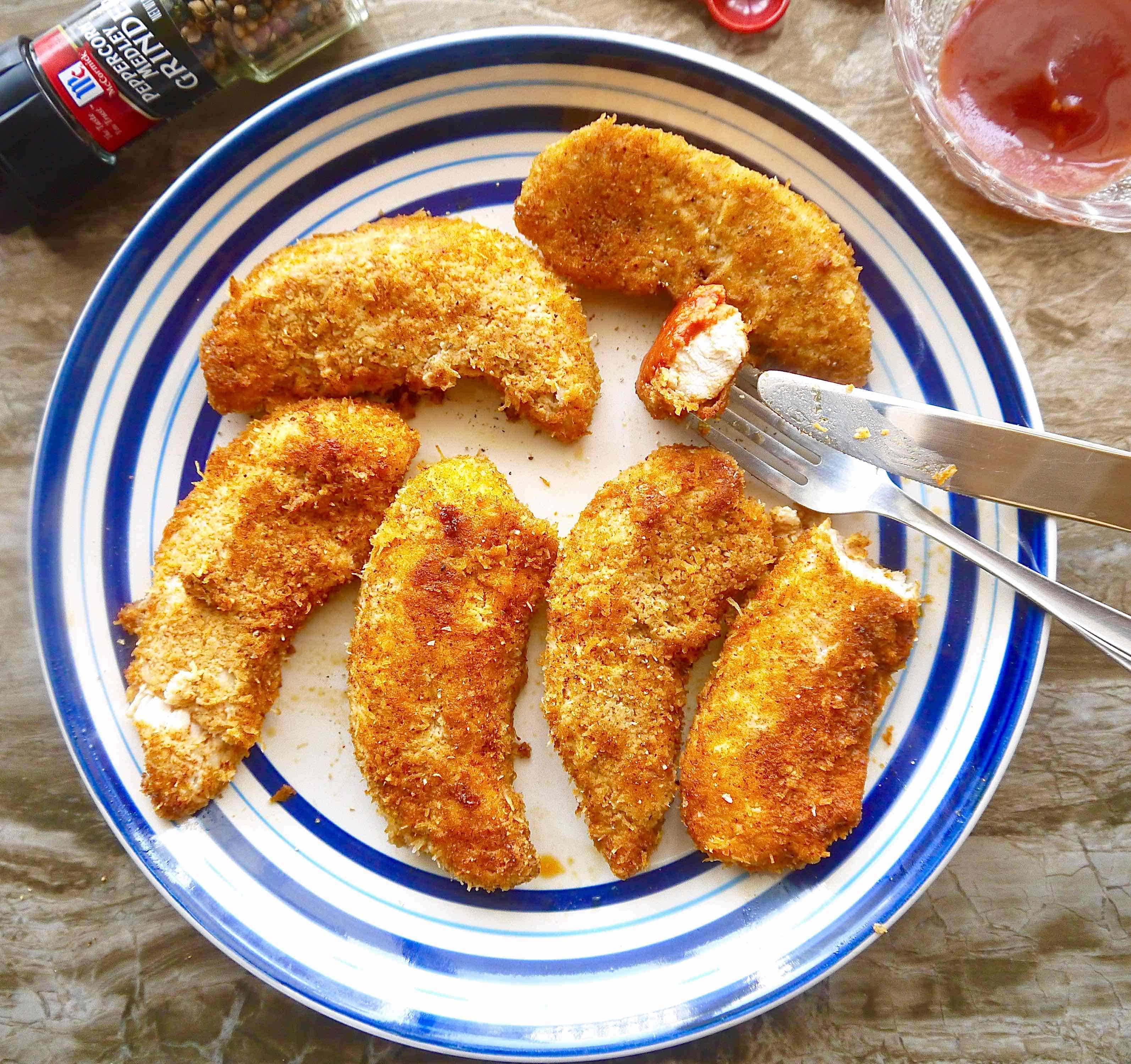 Baked Paleo Chicken Tenders with Shredded Coconut in a plate with a knife and fork.