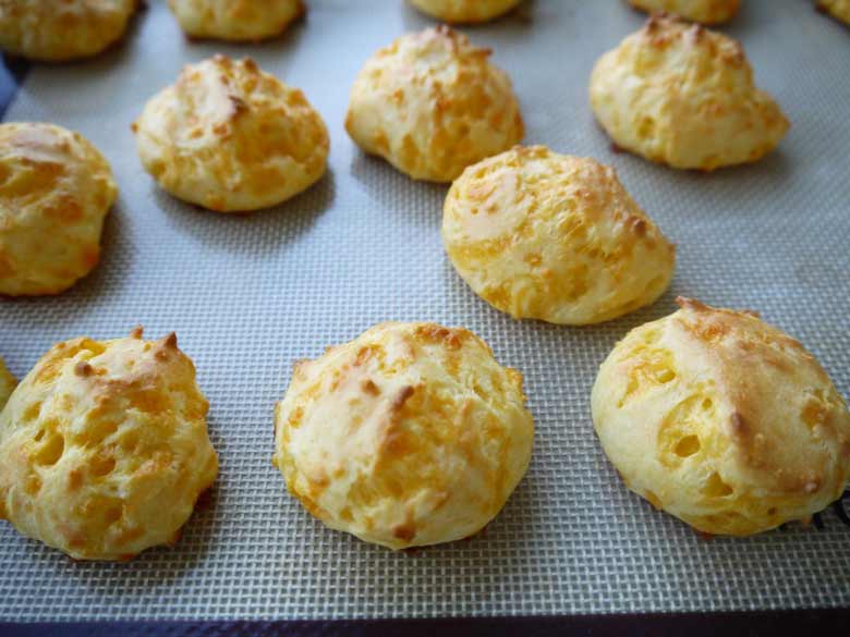 Fresh baked gougères on a pan.
