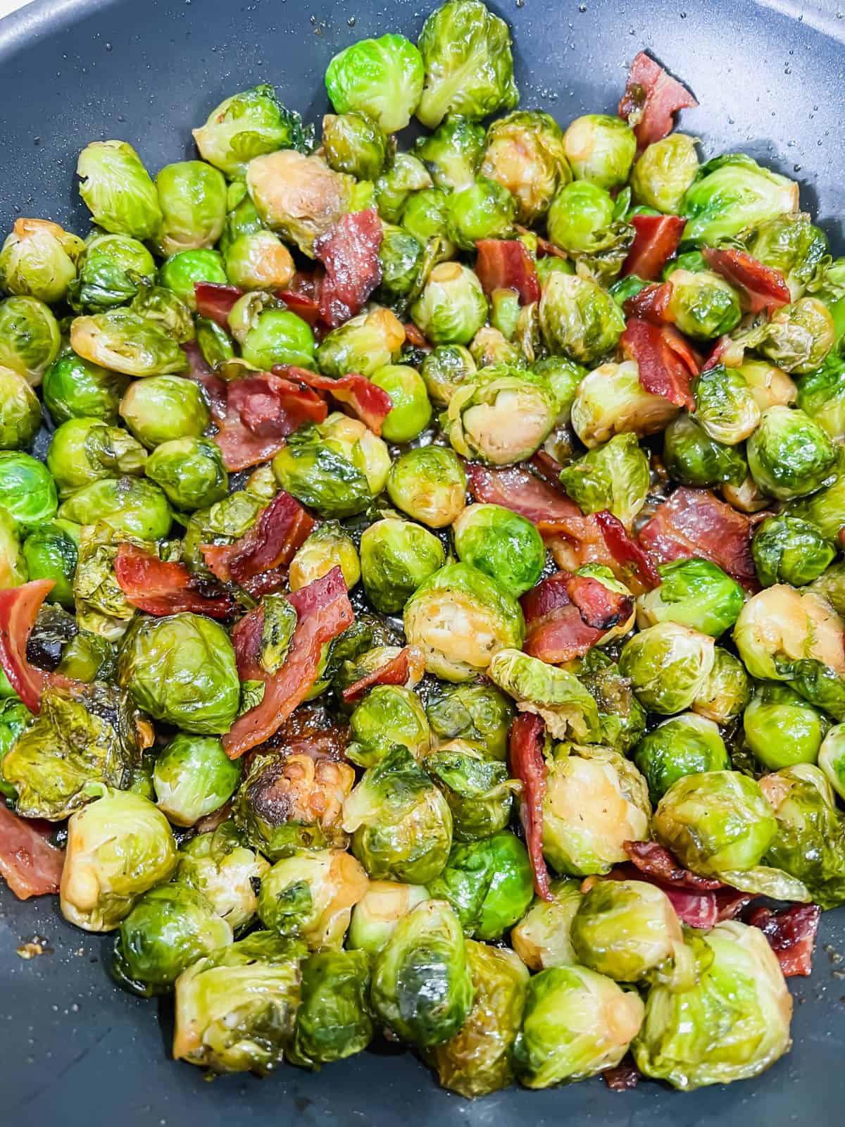 Maple brussel sprouts with bacon cooking in a frying pan.