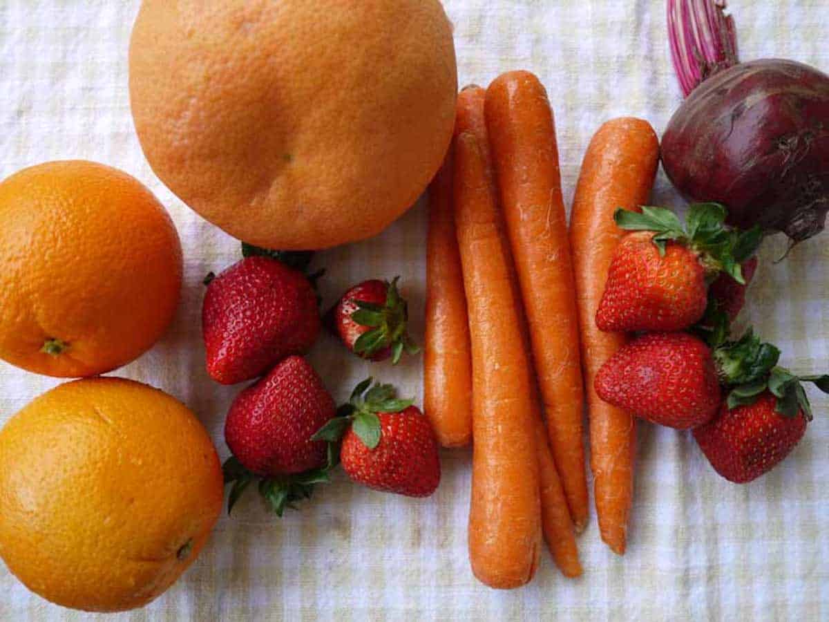 Ingredients needed to make strawberry beet orange carrot juice.