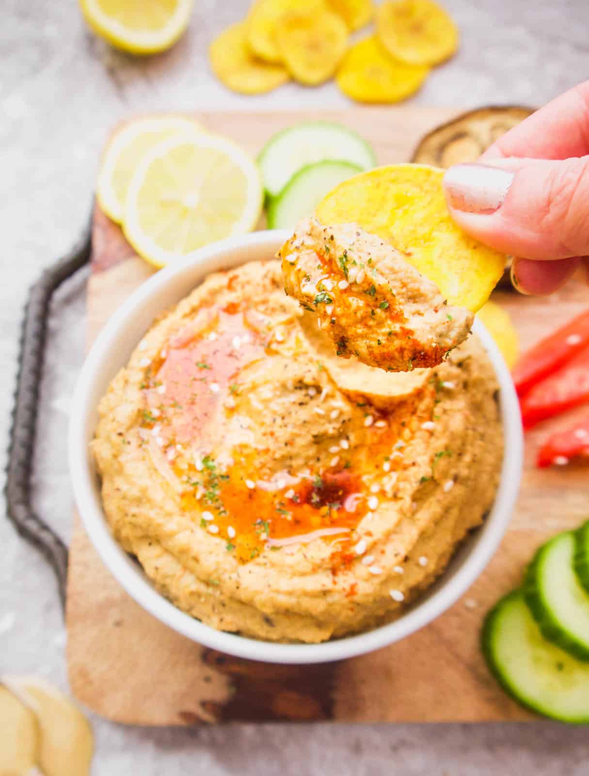 Mediterranean Cauliflower Hummus with a plantain chip lifting out of it.