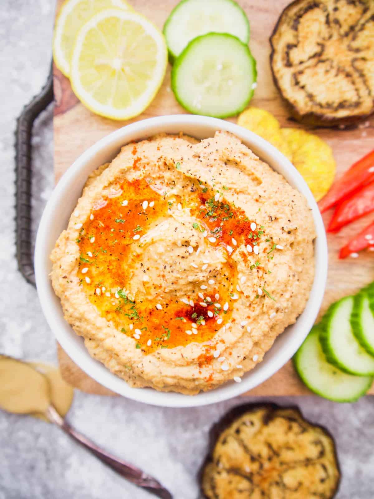 Cauliflower hummus in a bowl with roasted eggplant and peppers inside.