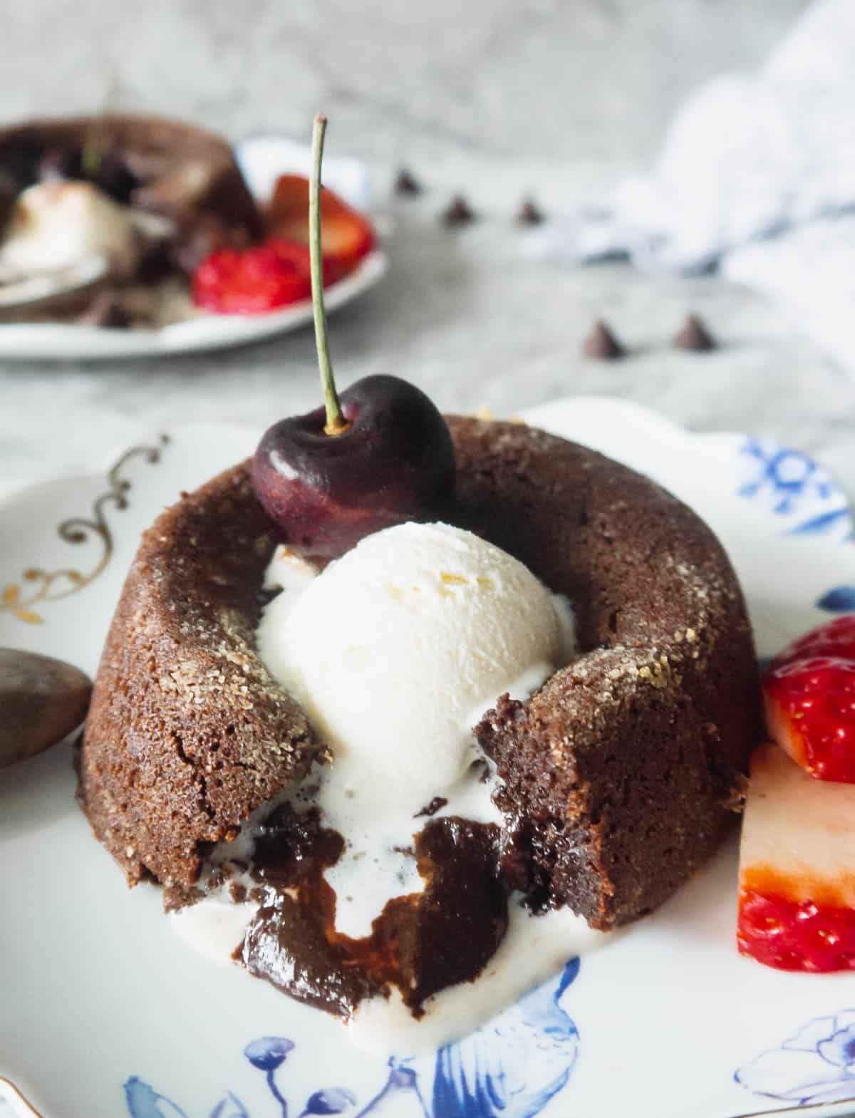 Gluten-free chocolate molten lava cake, with melted center coming out and topped in ice-cream that is melting.