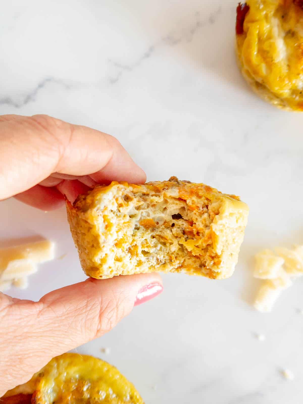 A bite taken out of a bacon sweet Potato breakfast muffin.