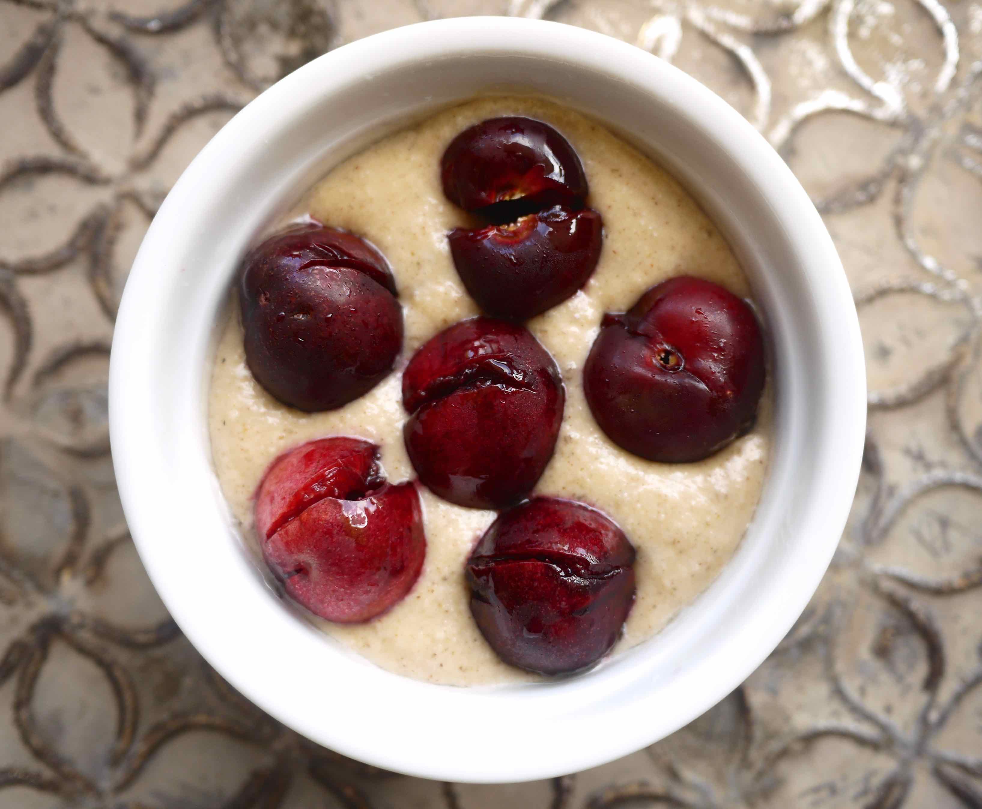 Cherry Clafoutis batter in a ramekin with cherries added.