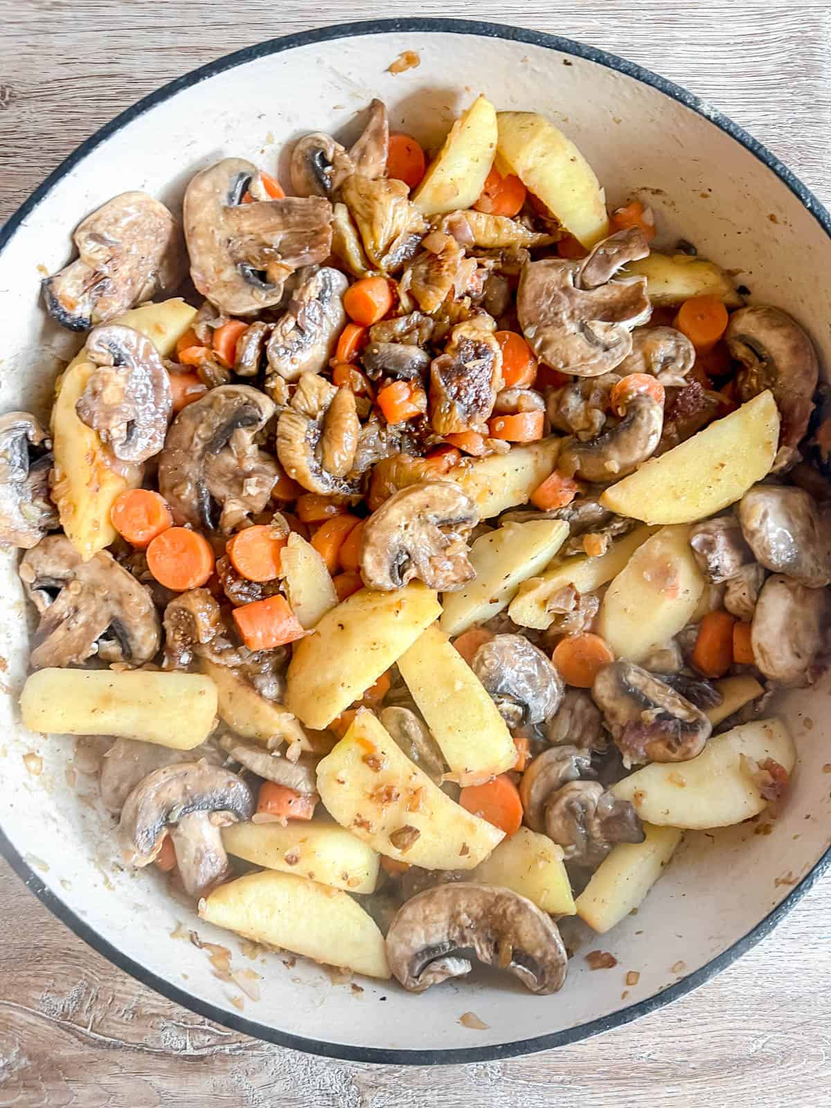 Apples, carrots, mushrooms, and figs added to a dutch oven.