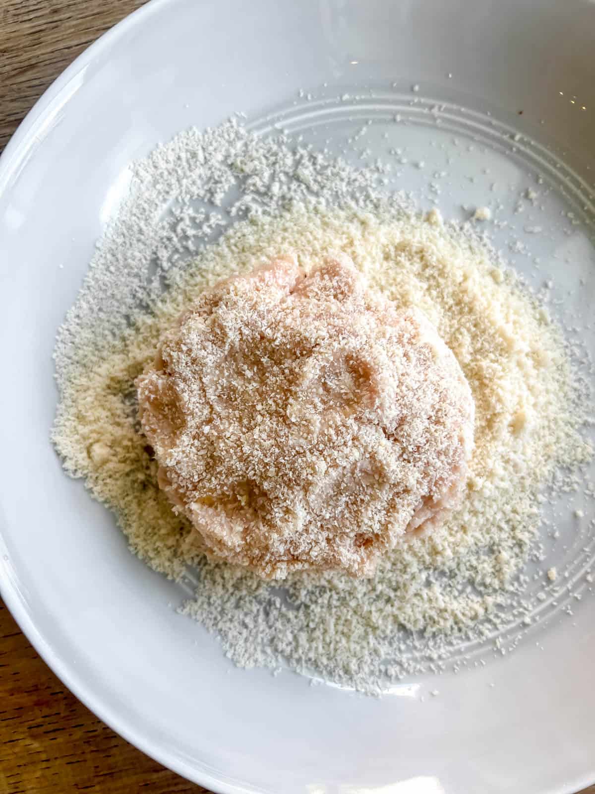 A chicken burger patty dunked in almond flour.