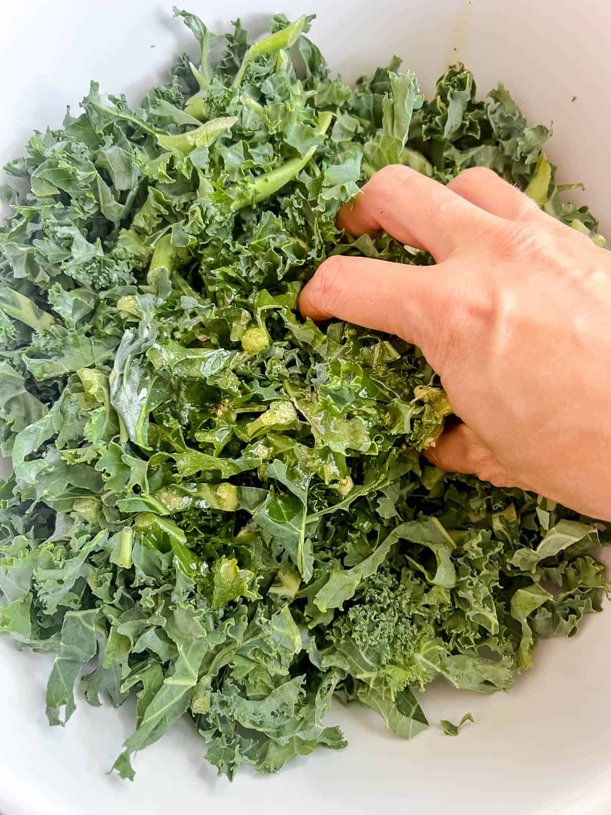 Kale being massaged in a bowl.