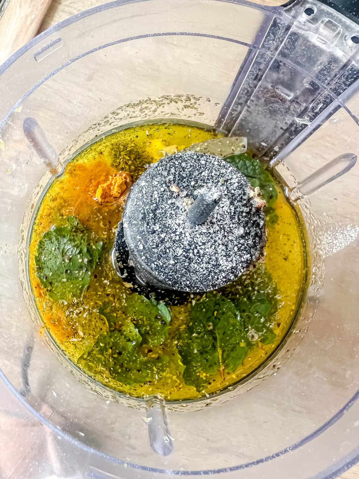 Ingredients in a food processor to make lemon mint dressing with turmeric powder.
