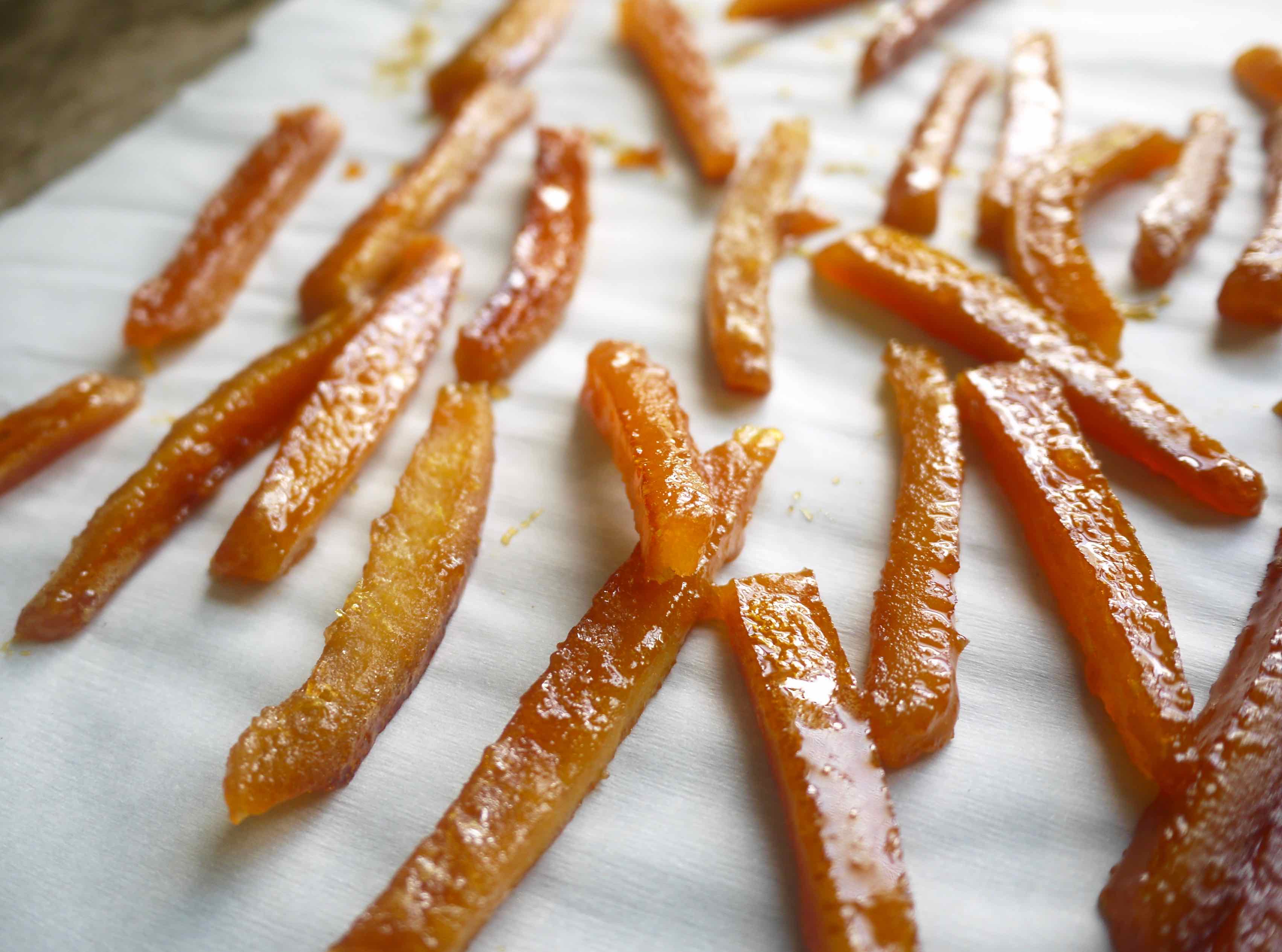 Freshly candied orange peels drying on parchment paper.