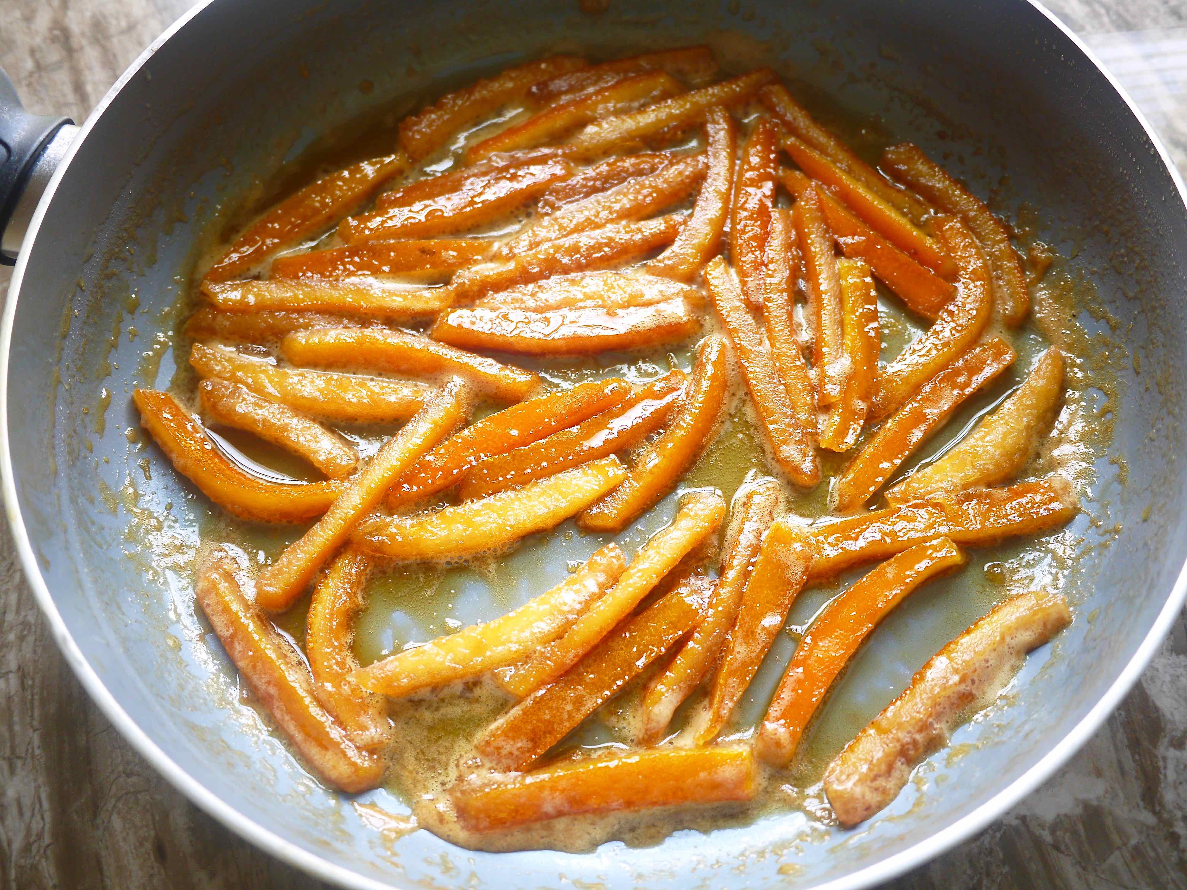 Orange peels in a pan covered in honey and water.