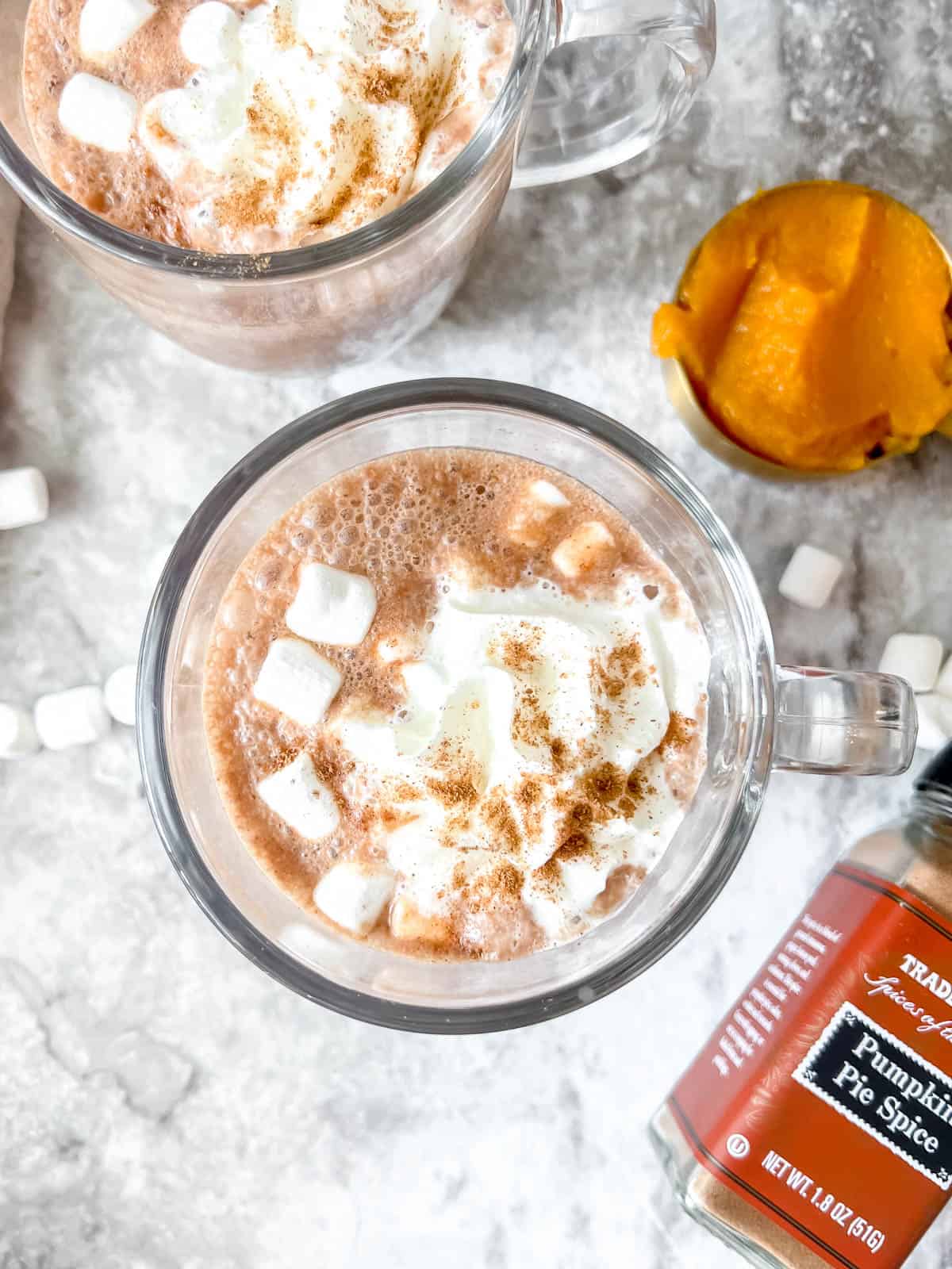 Aerial view of pumpkin hot chocolate recipe with marshmallows and whipped cream on top.
