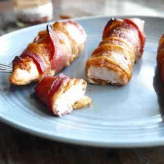 Piece of bacon wrapped chicken cut on a plate.