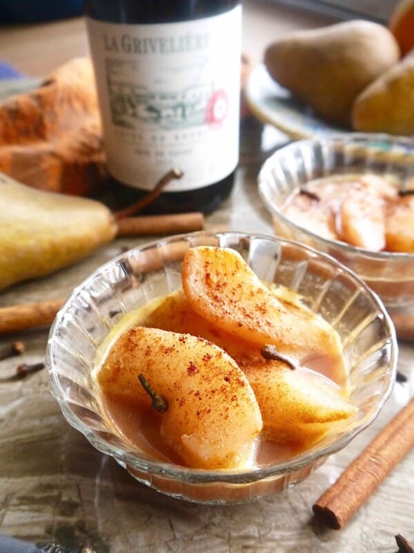 Spiced Poached Pears in a bowl with a red wine and orange juice sauce.