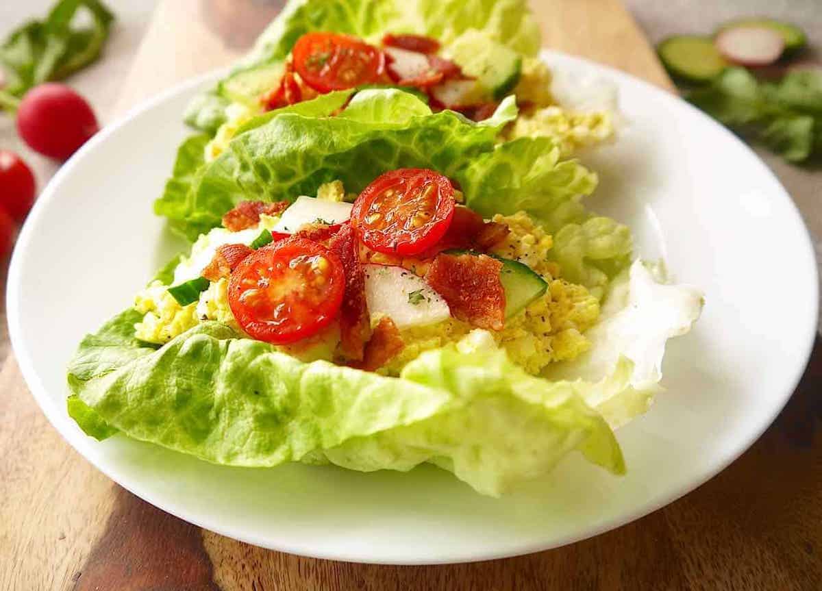 Egg Salad Lettuce Wraps with radish, tomatoes and cucumber on top.