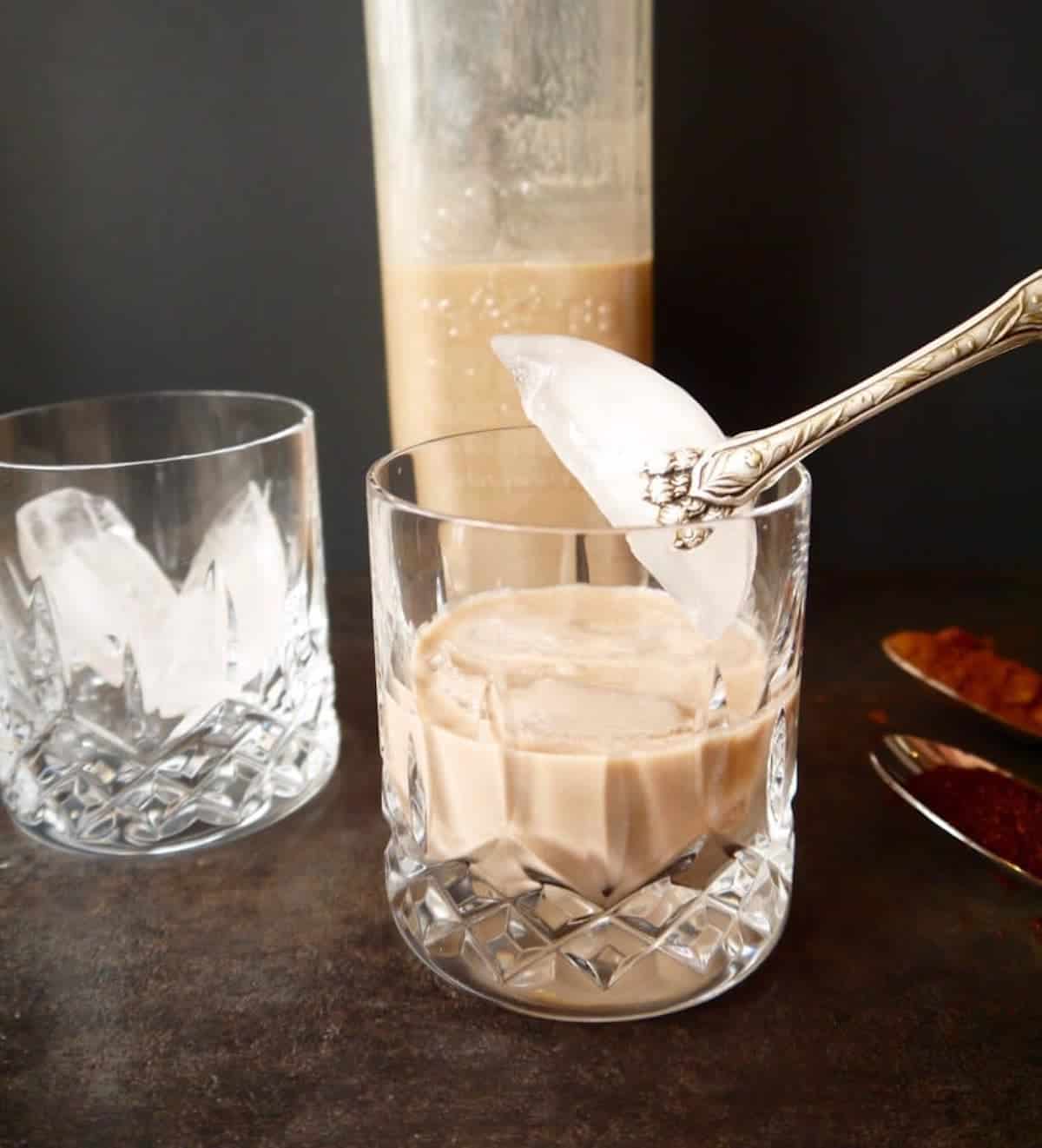 Dairy free baileys in a glass with ice being put into the glass.