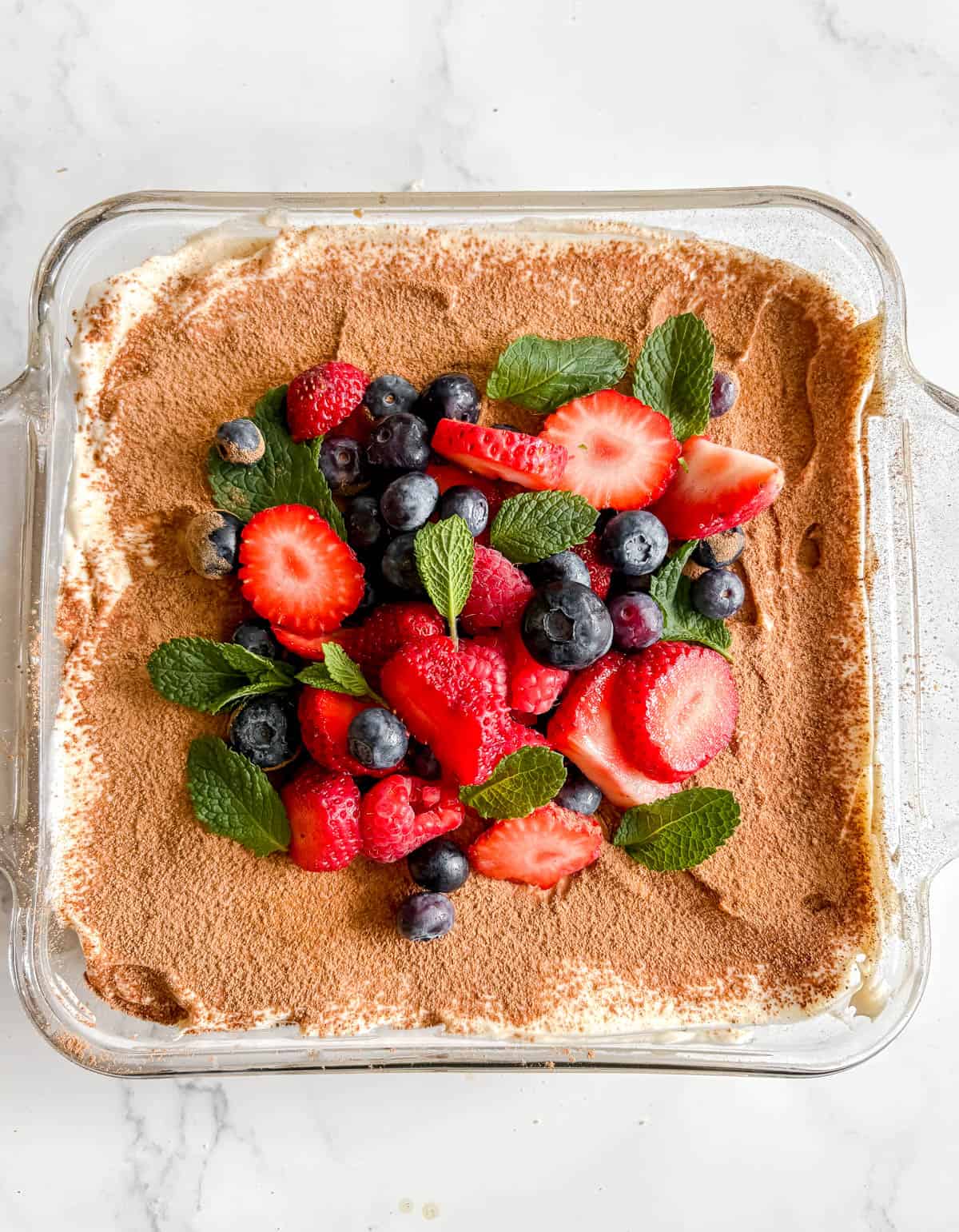 Berries and mint on top of coconut cream tiramisu.