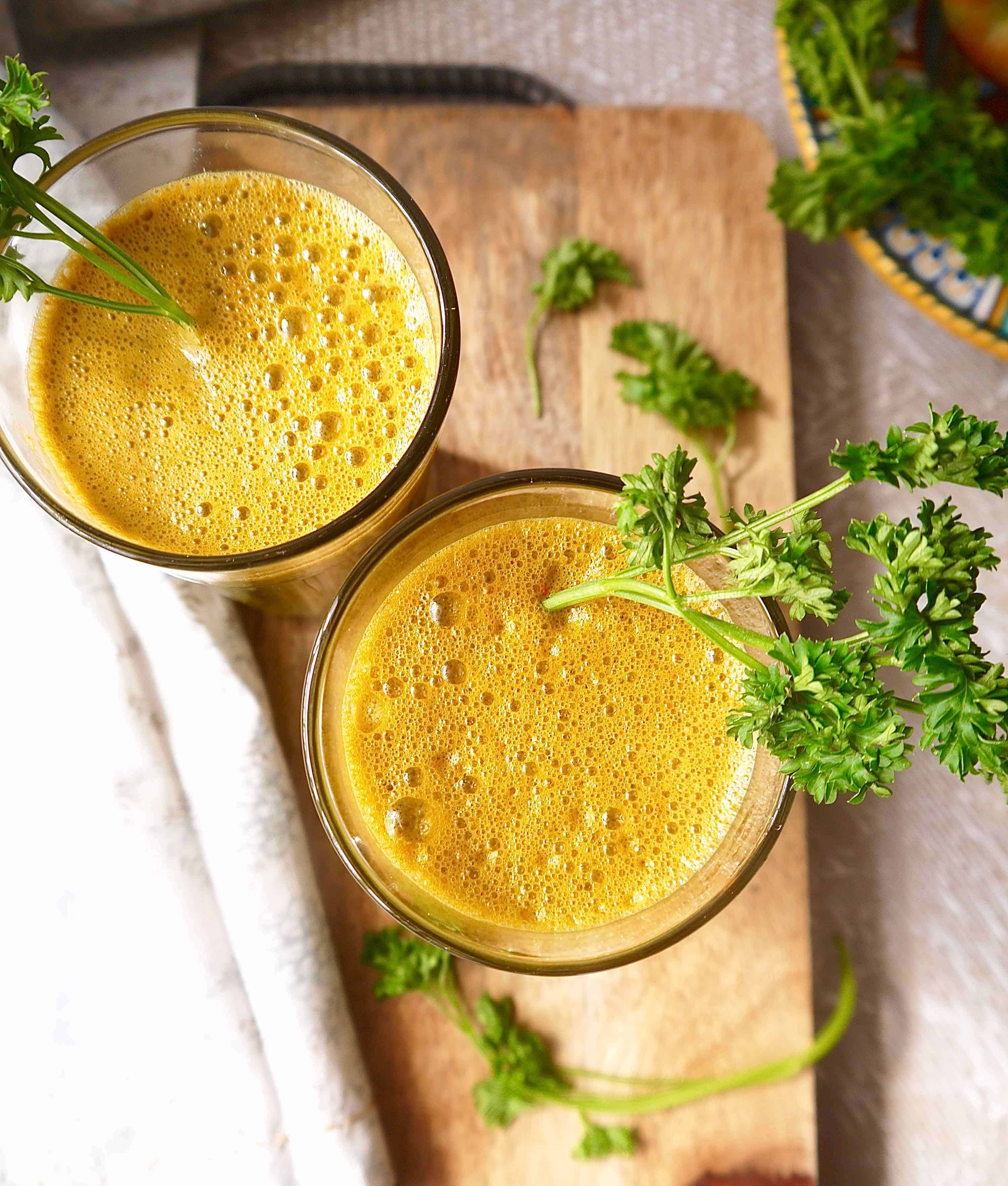 Carrot Kale Apple Juice with Parsley in two cups on a table.