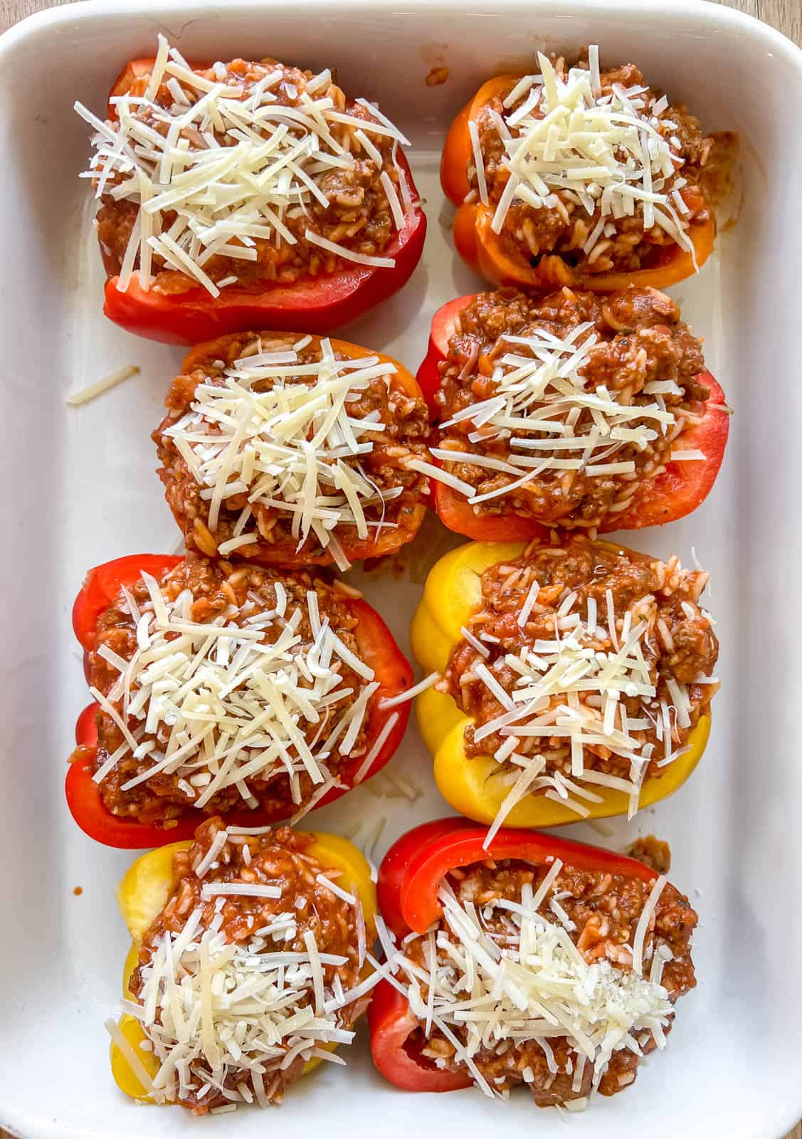 Cheese sprinkled on top of stuffed peppers before baking.