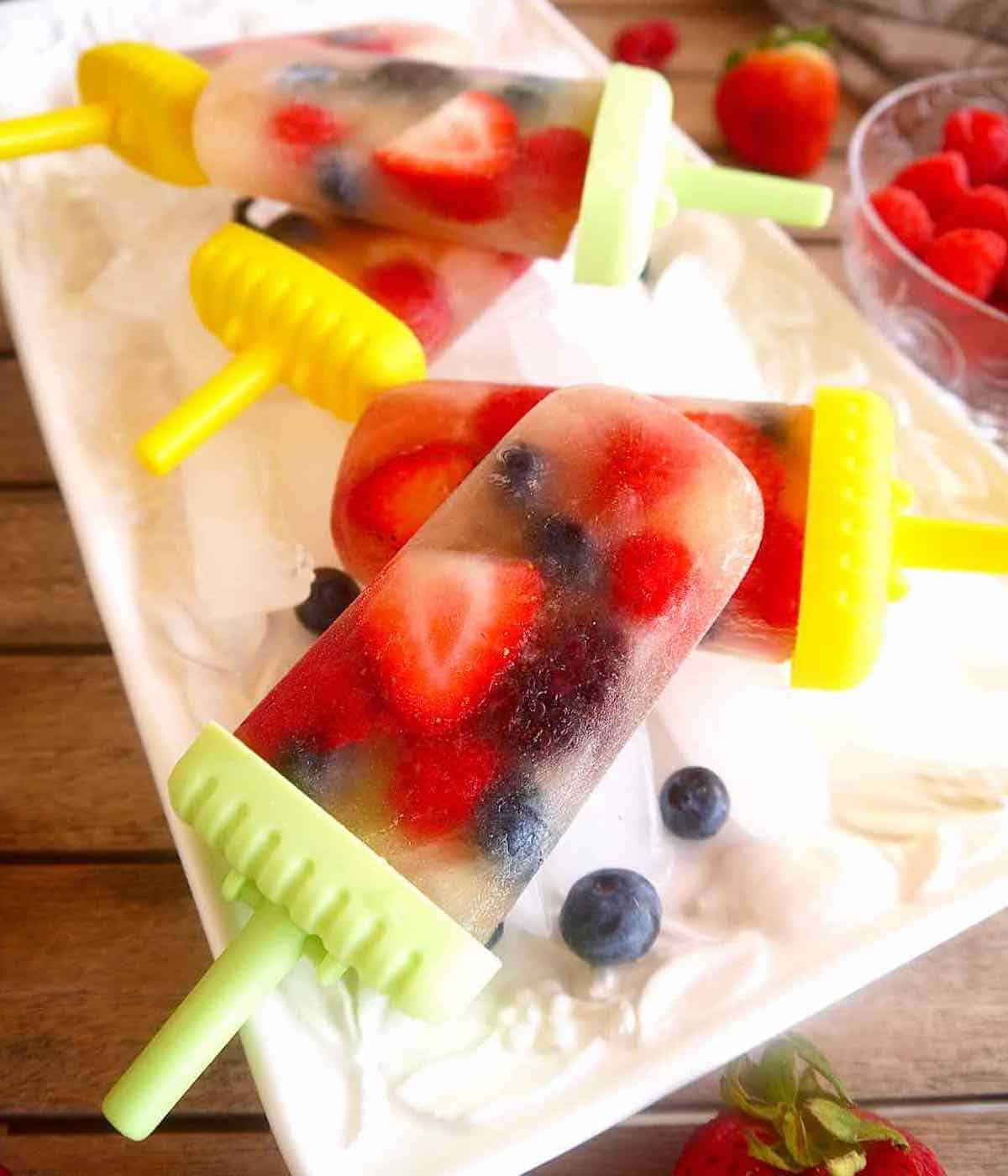Apple juice popsicles with berries on ice.