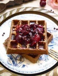 Gluten-free Chocolate Cherry Waffles on a plate with cherries on top.