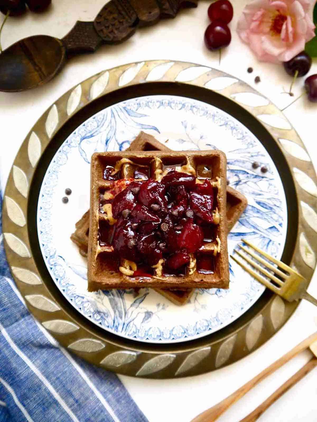 Gluten free chocolate waffles with cherry compote on top.