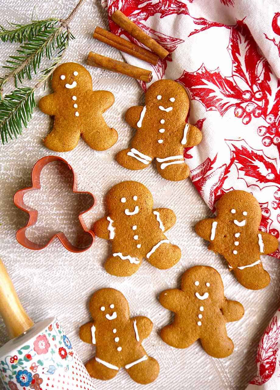 Several gingerbread men cookies on a table with cookie cutters and decorations.