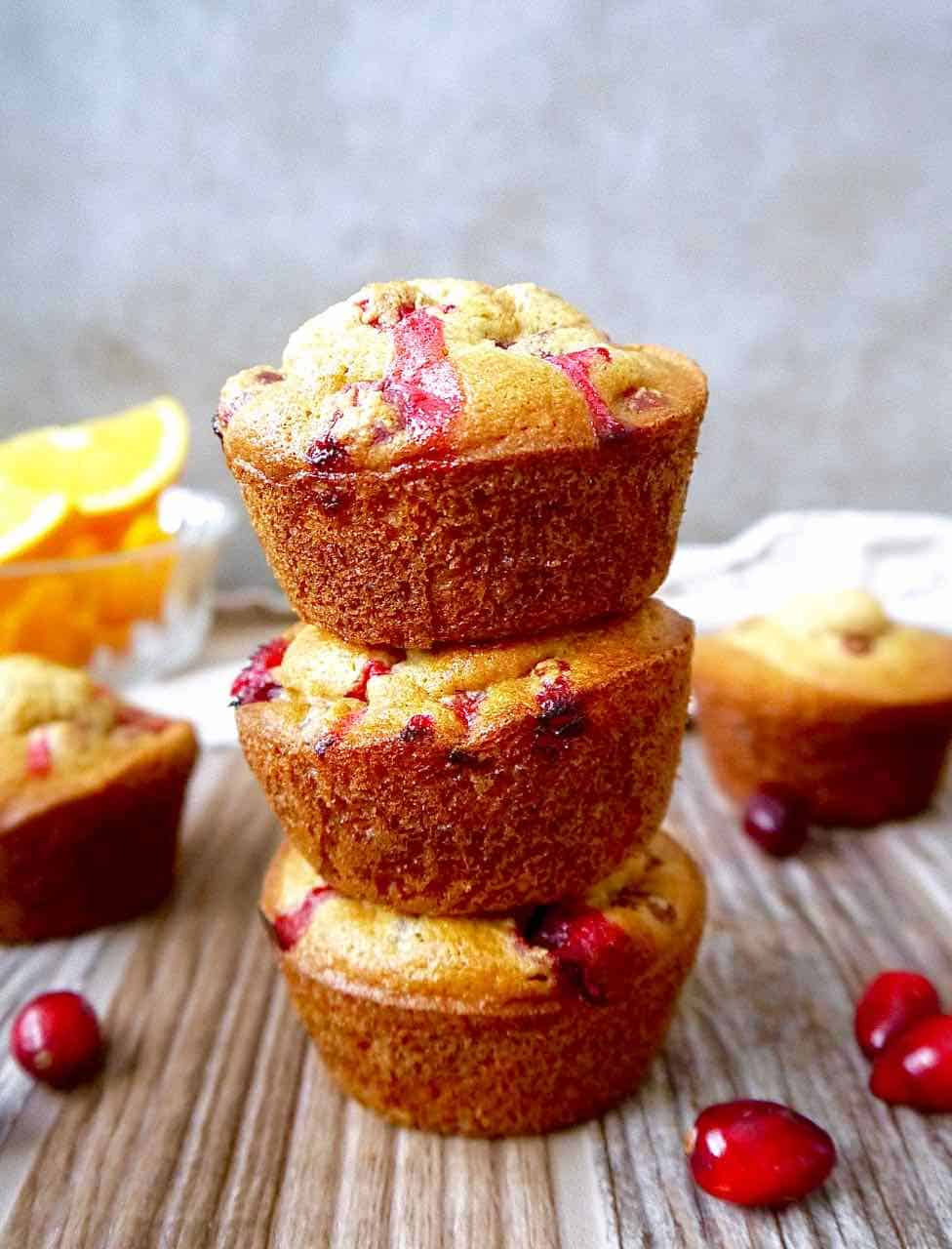 Three orange cranberry muffins stacked on top of each other. 