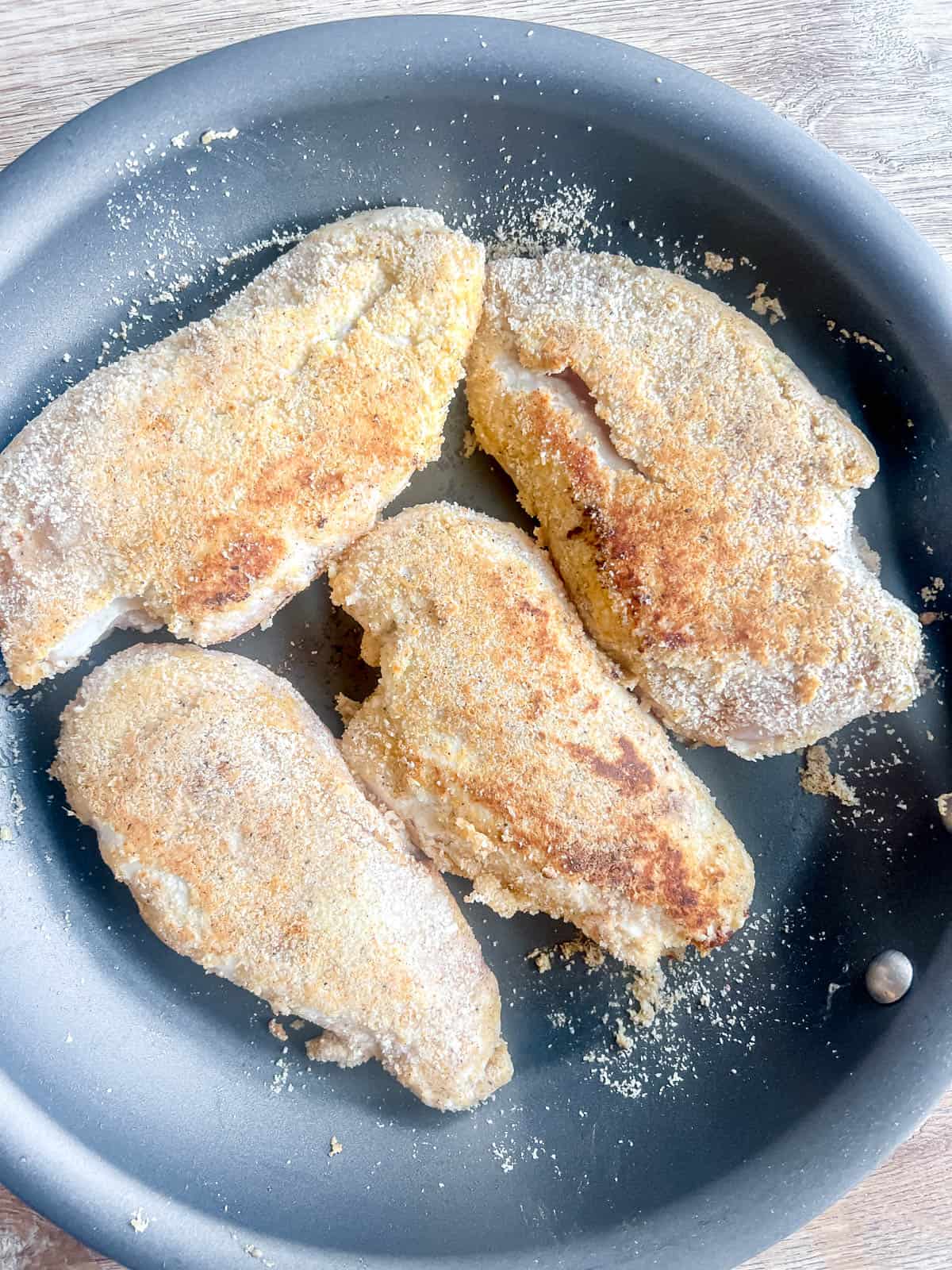 Breaded chicken breast in a pan and grilled.