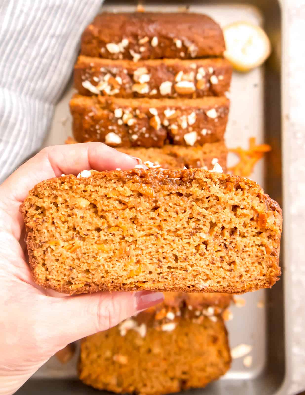 A slice of Paleo Carrot Cake Banana Bread lifted by hands.