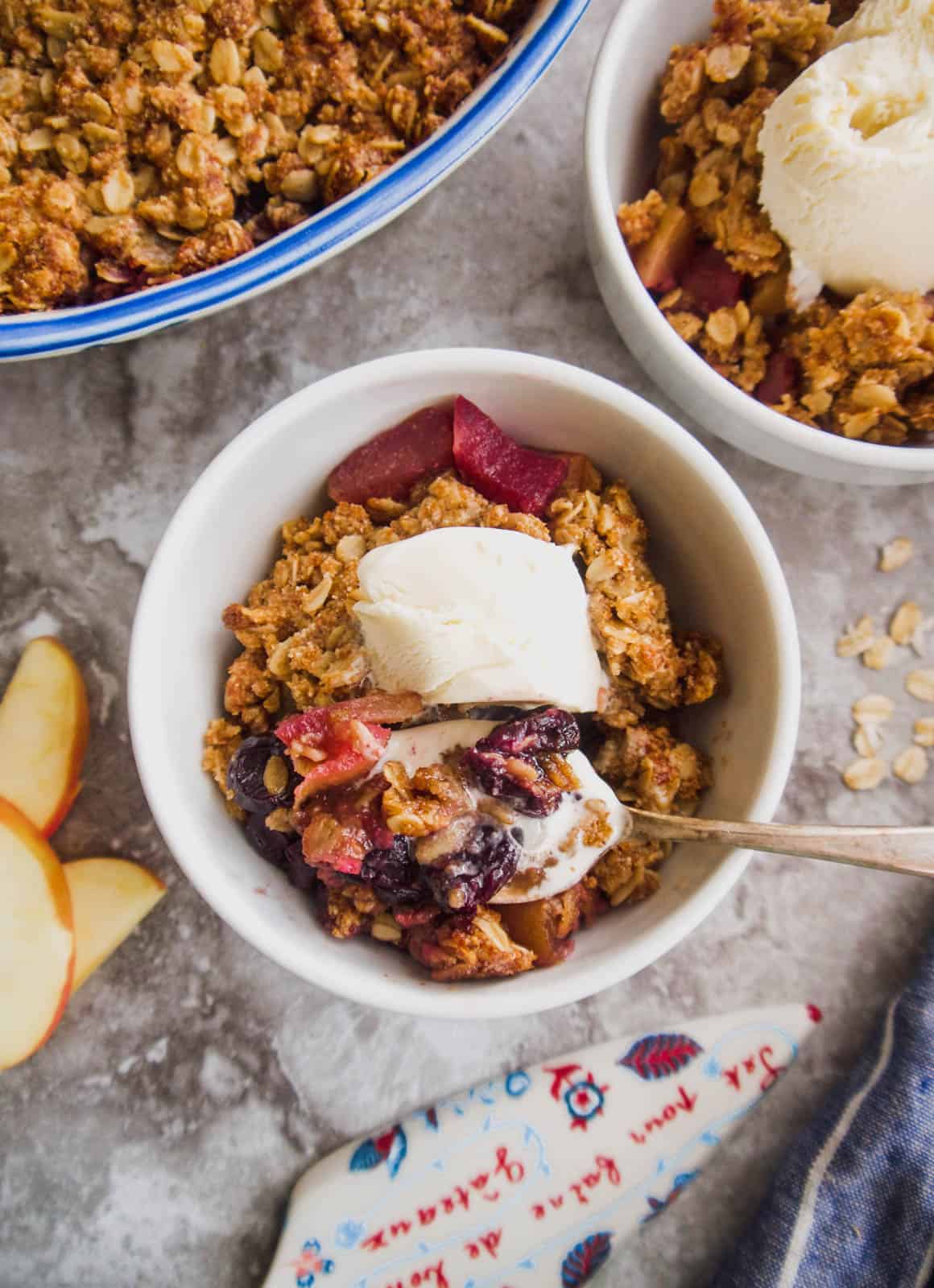 Cherry apple crisp in two bowls with ice-cream on top.