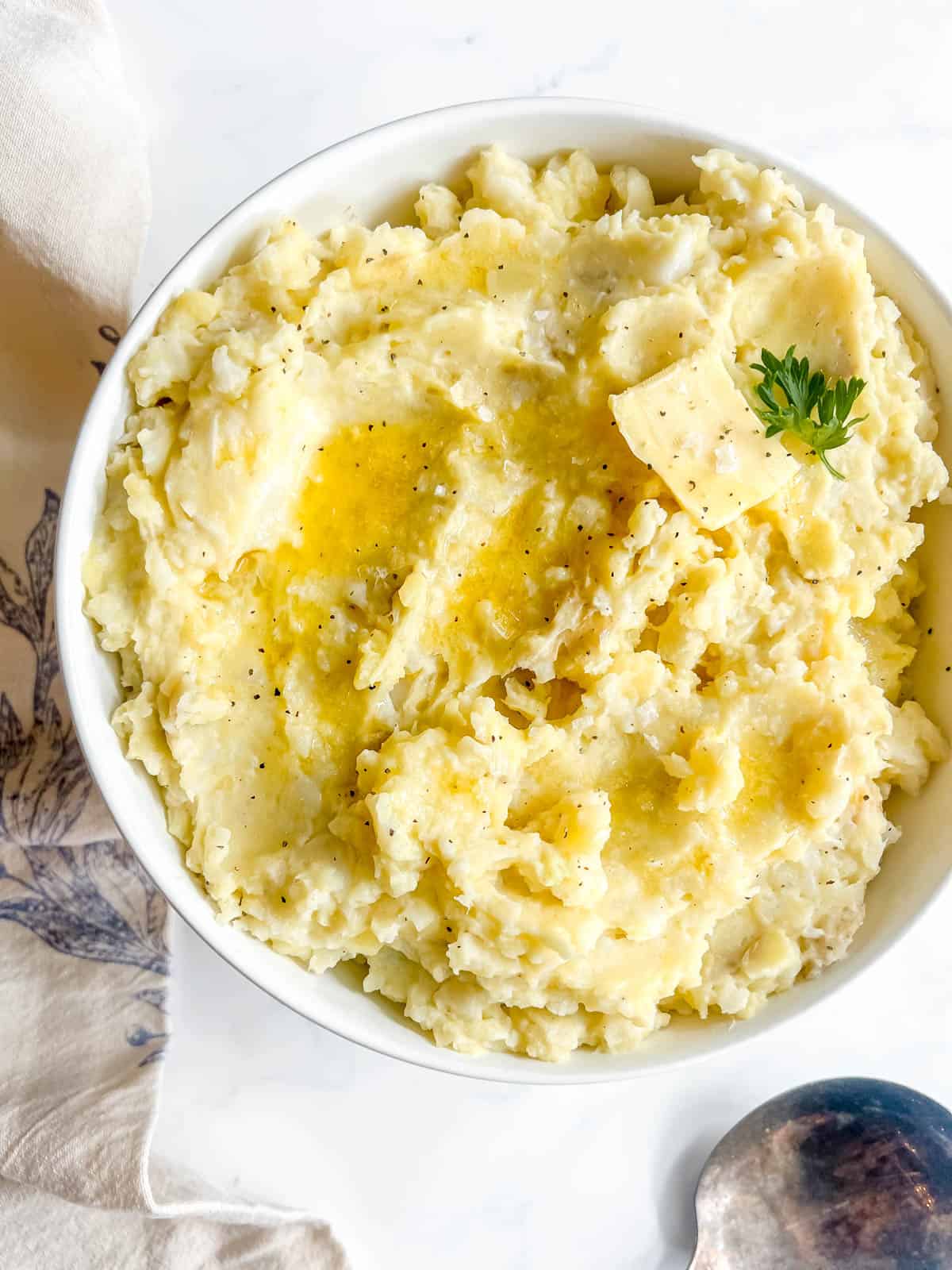Cauliflower and Potato Mash in a serving bowl with butter on top.