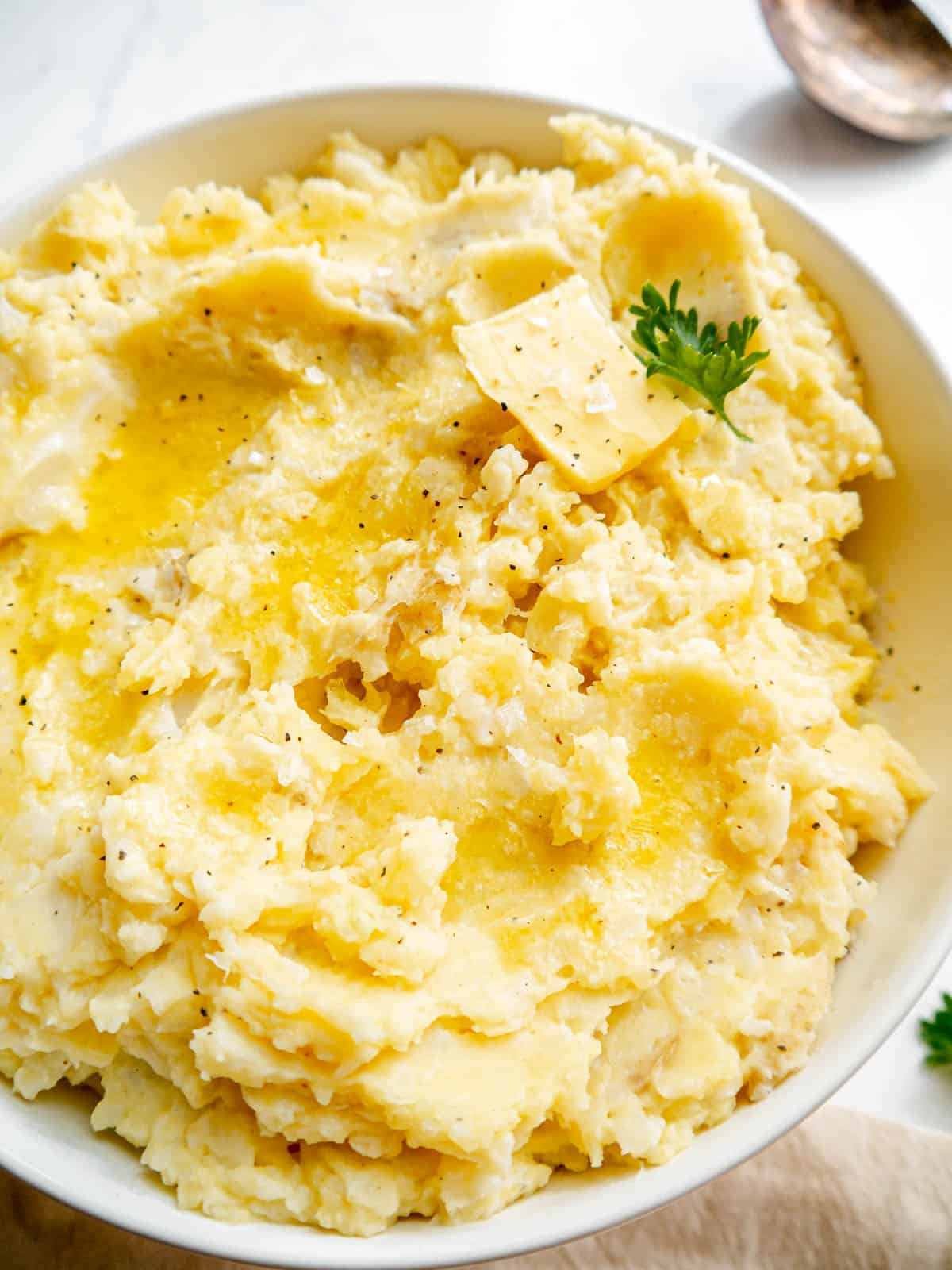 Cauliflower and potato mash in a serving bowl with butter on top.