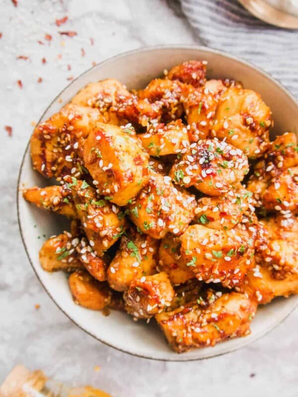 Healthy Honey Sesame Chicken in a bowl covered in extra sesame seeds