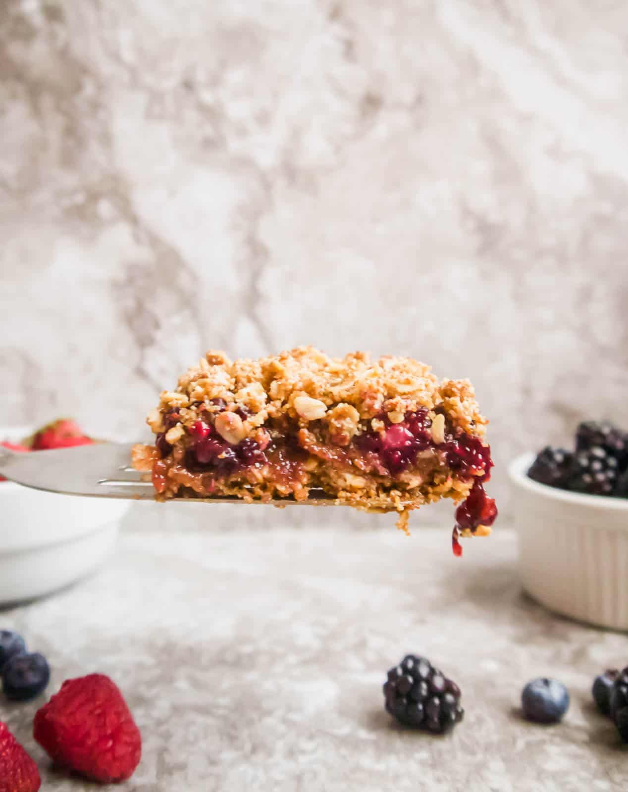 A slice of a berry oat bar being lifted out of the pan.