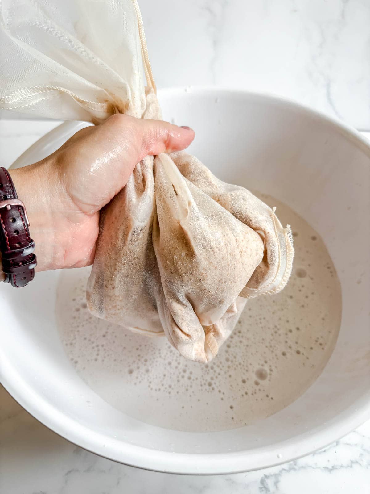 Squeezing the almond milk bag.