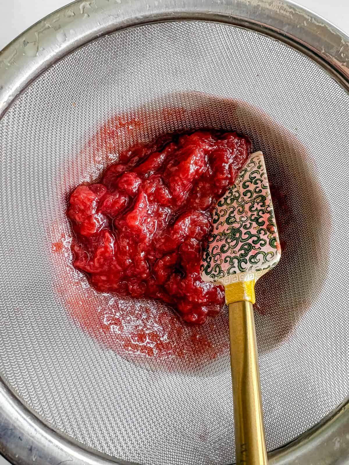 Straining the strawberry pulp from the syrup.