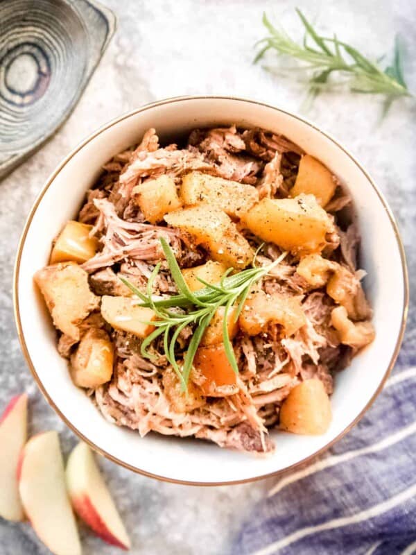Apple pulled pork in a bowl with cooked apples on top.