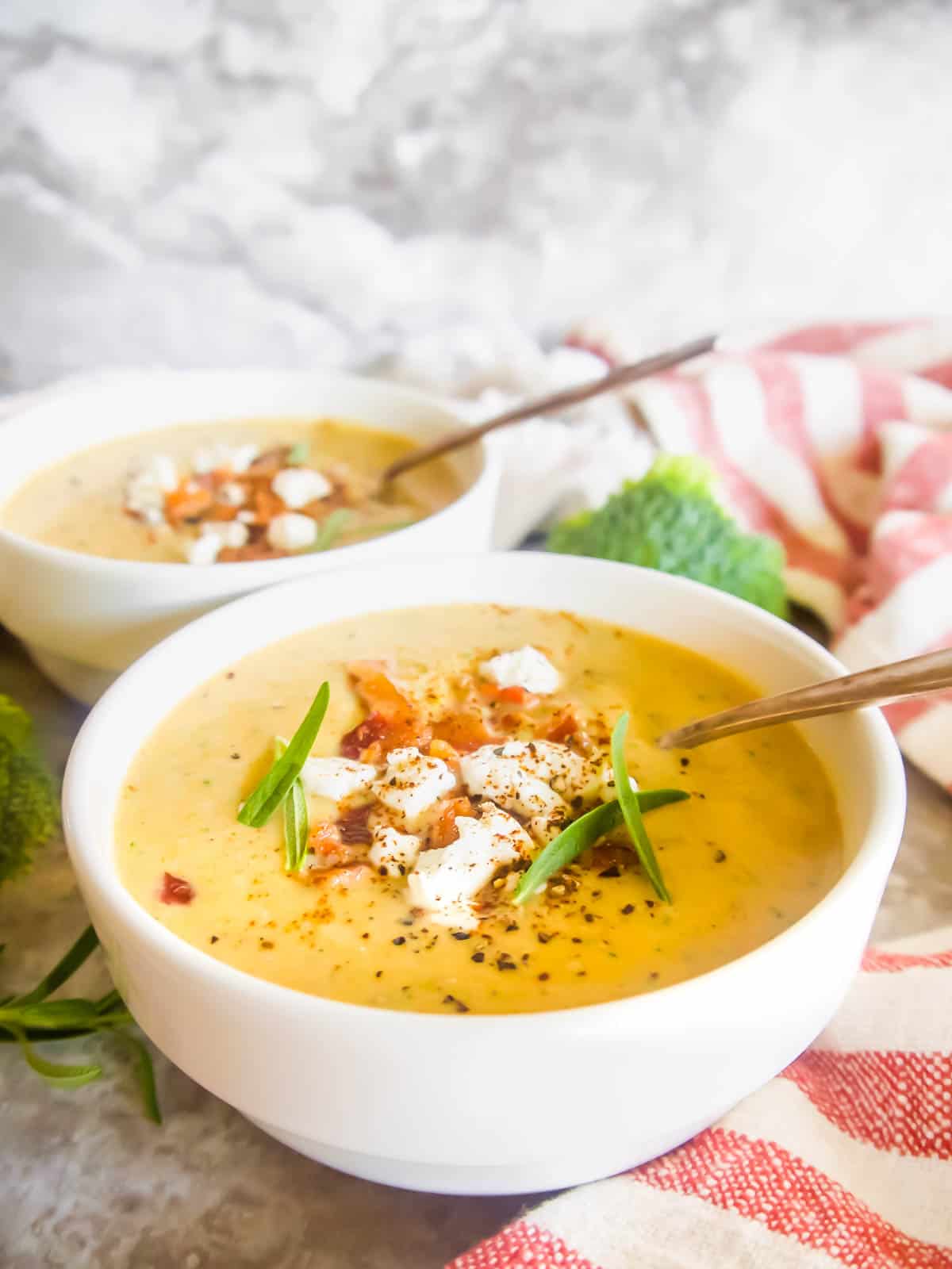 Broccoli and sweet potato soup in two bowls with bacon on top.