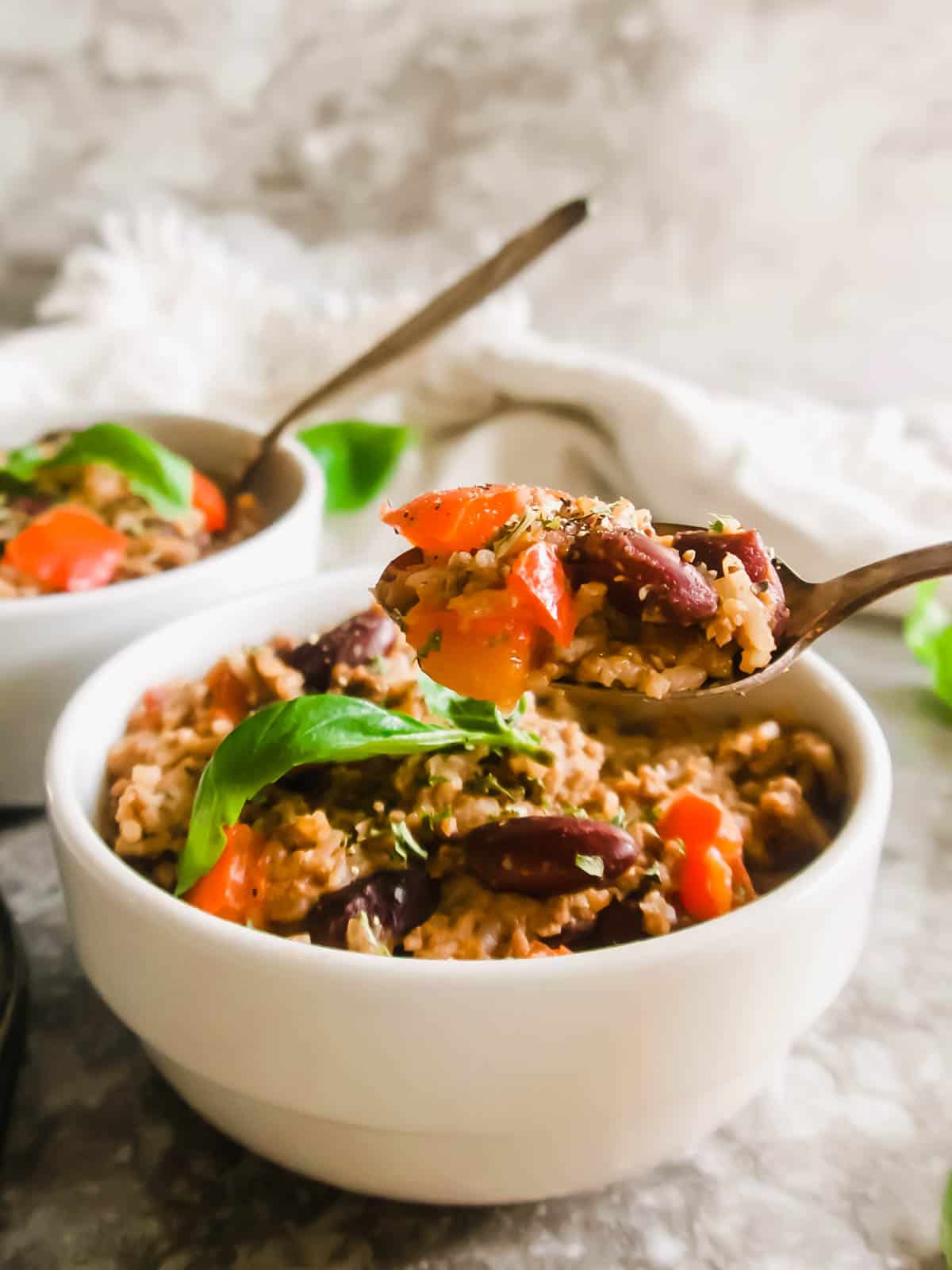 Spoon being lifted out of a bowl with turkey rice and bean casserole inside.