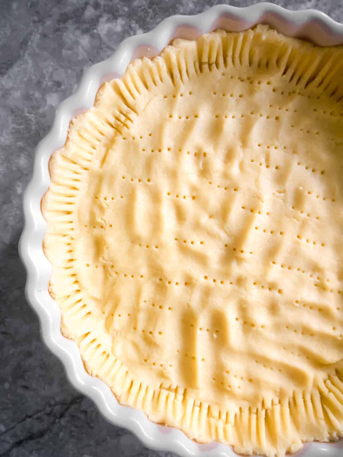 Raw dough spread out in tart pan.