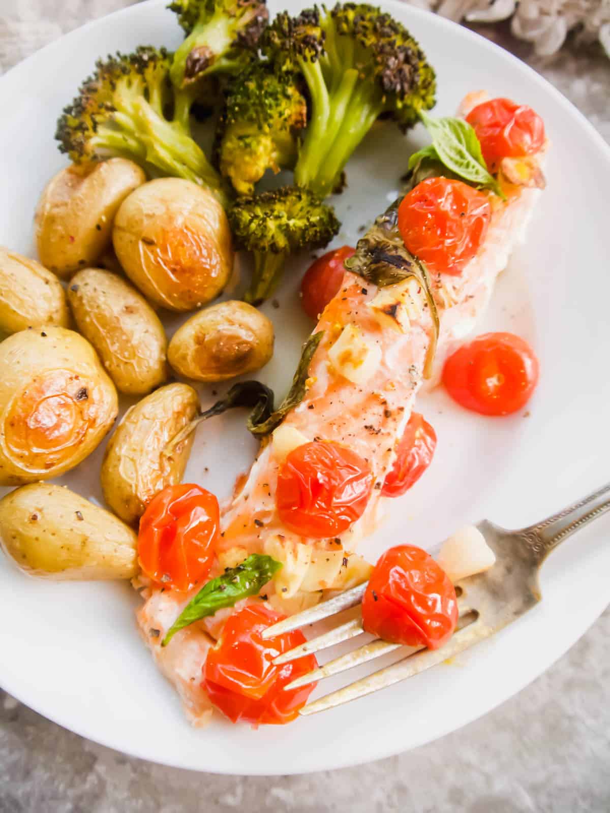 Salmon and tomatoes on a plate with potatoes.