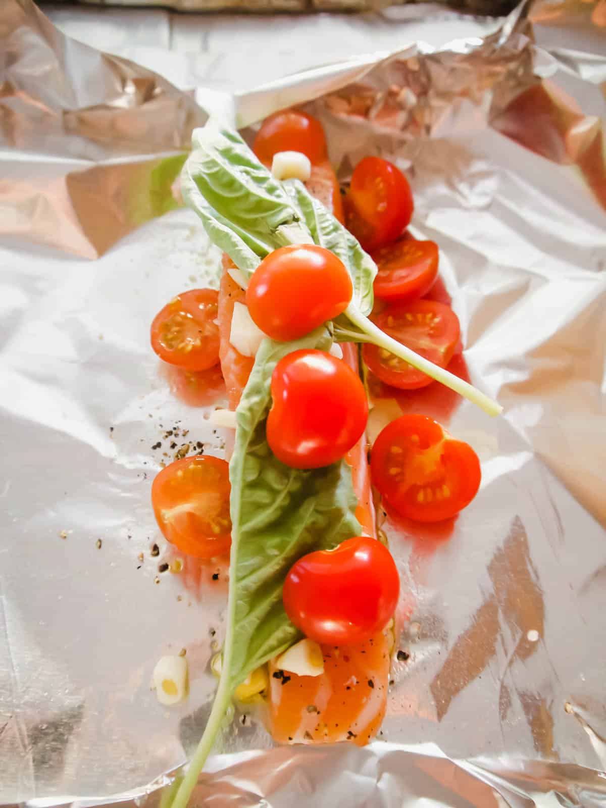 Salmon with garlic, basil, and cherry tomatoes on top.