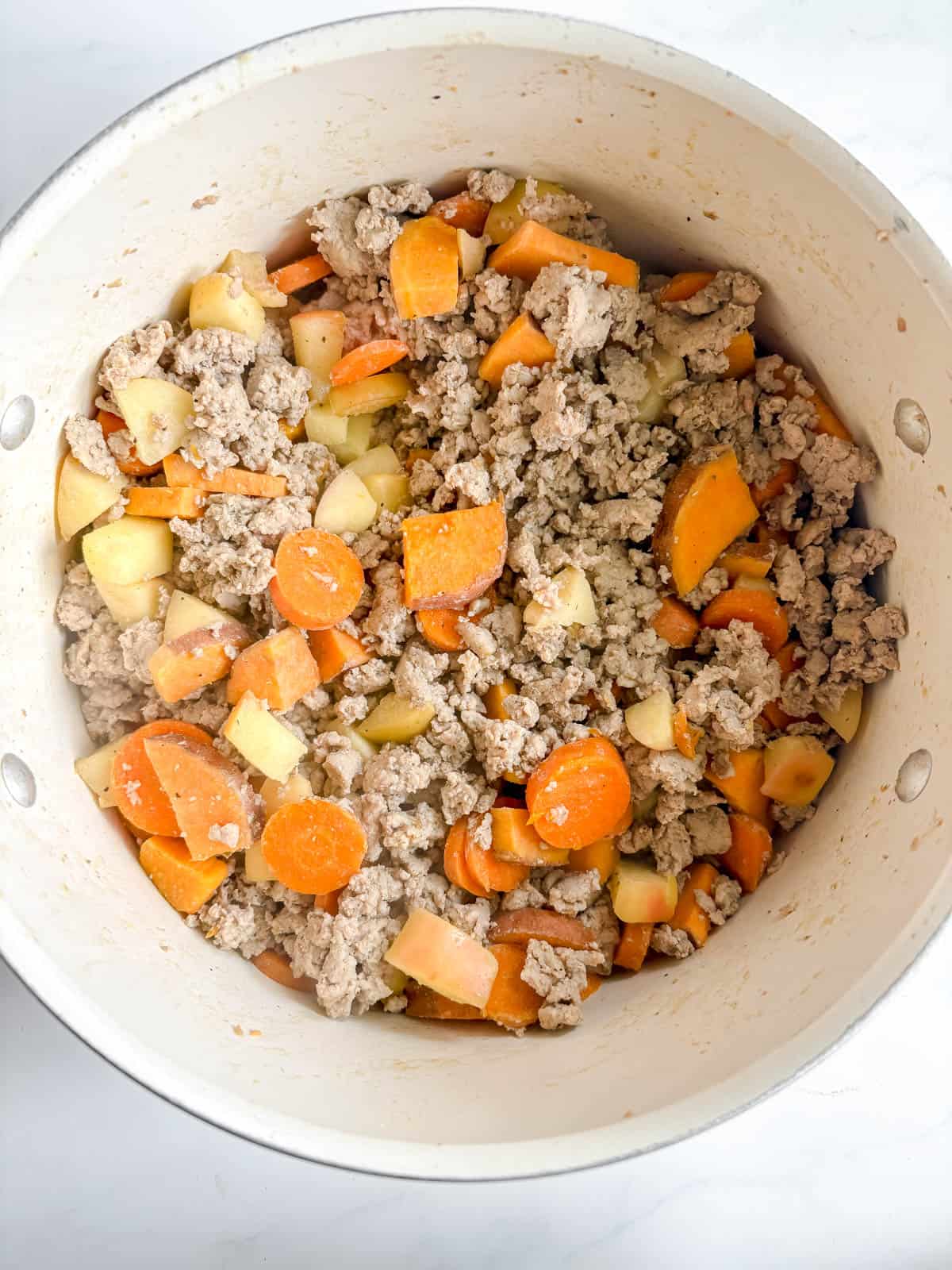 Ground turkey added to a pot to make turkey apple chili.