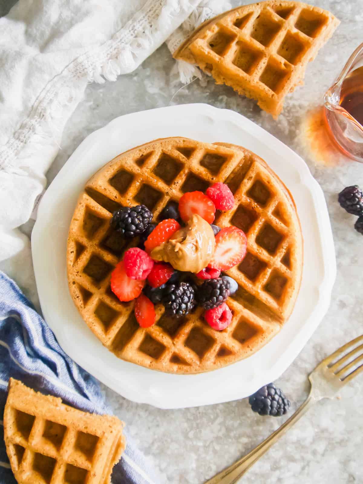 Paleo waffle on a plate with fruit on top.