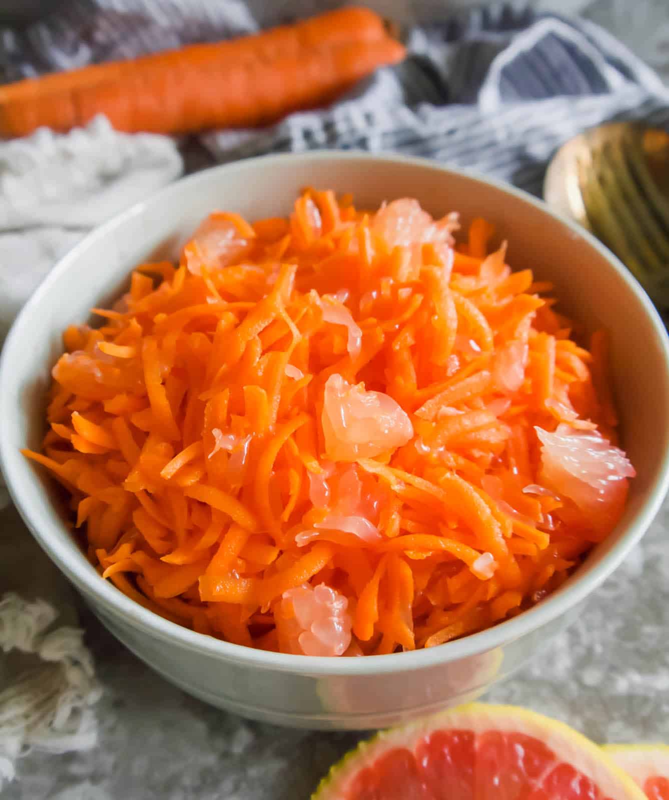 Raw carrot salad with grapefruit in a bowl on a plate.