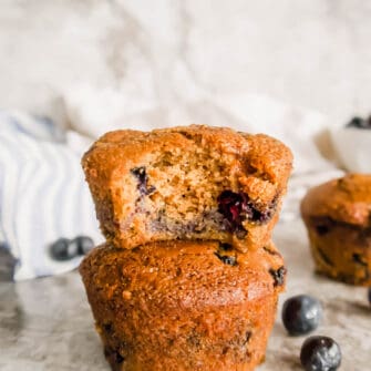 Paleo blueberry muffins on top of each other with a bite taken out.