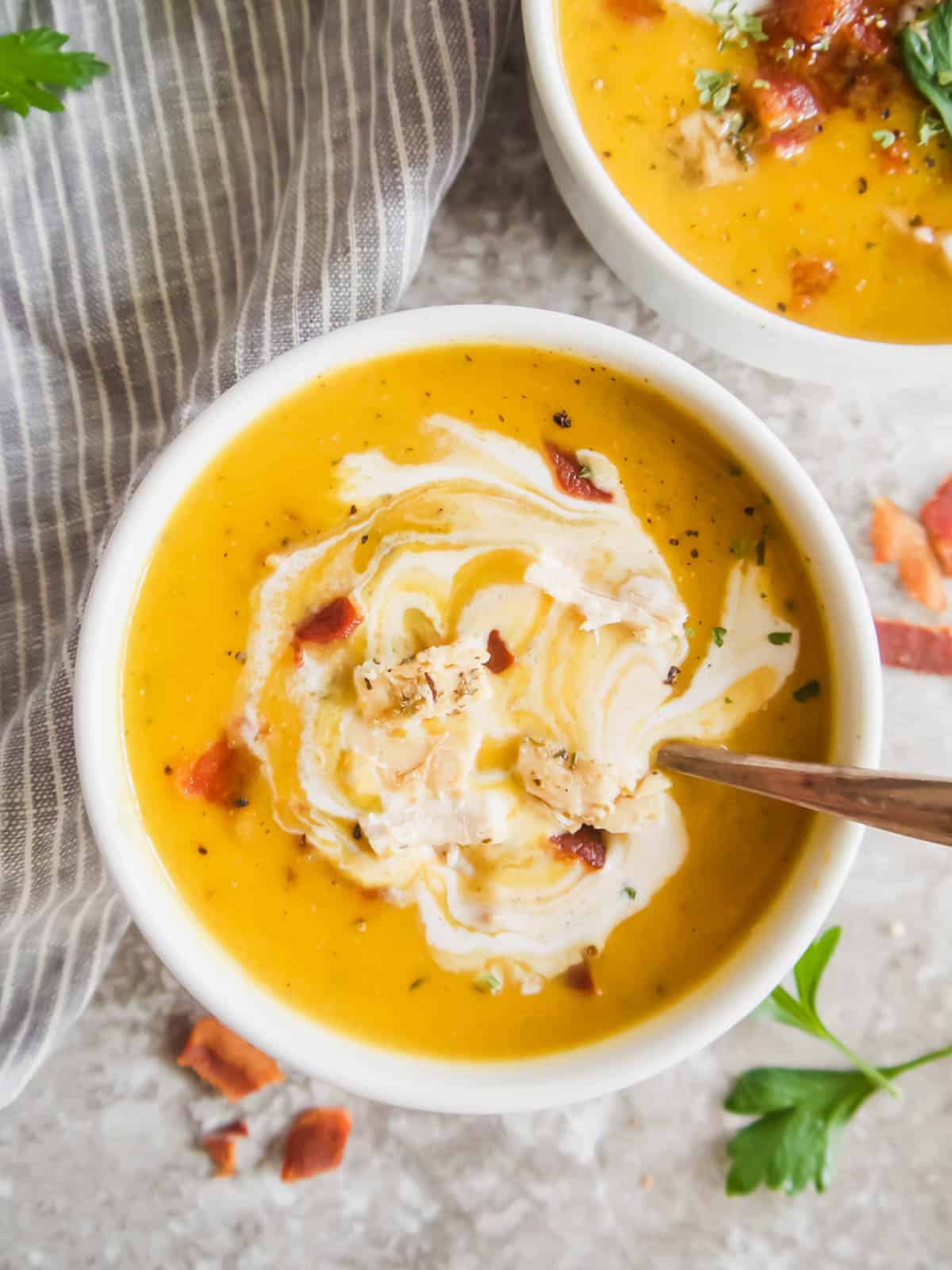 Butternut squash soup with bacon and chicken inside of it.