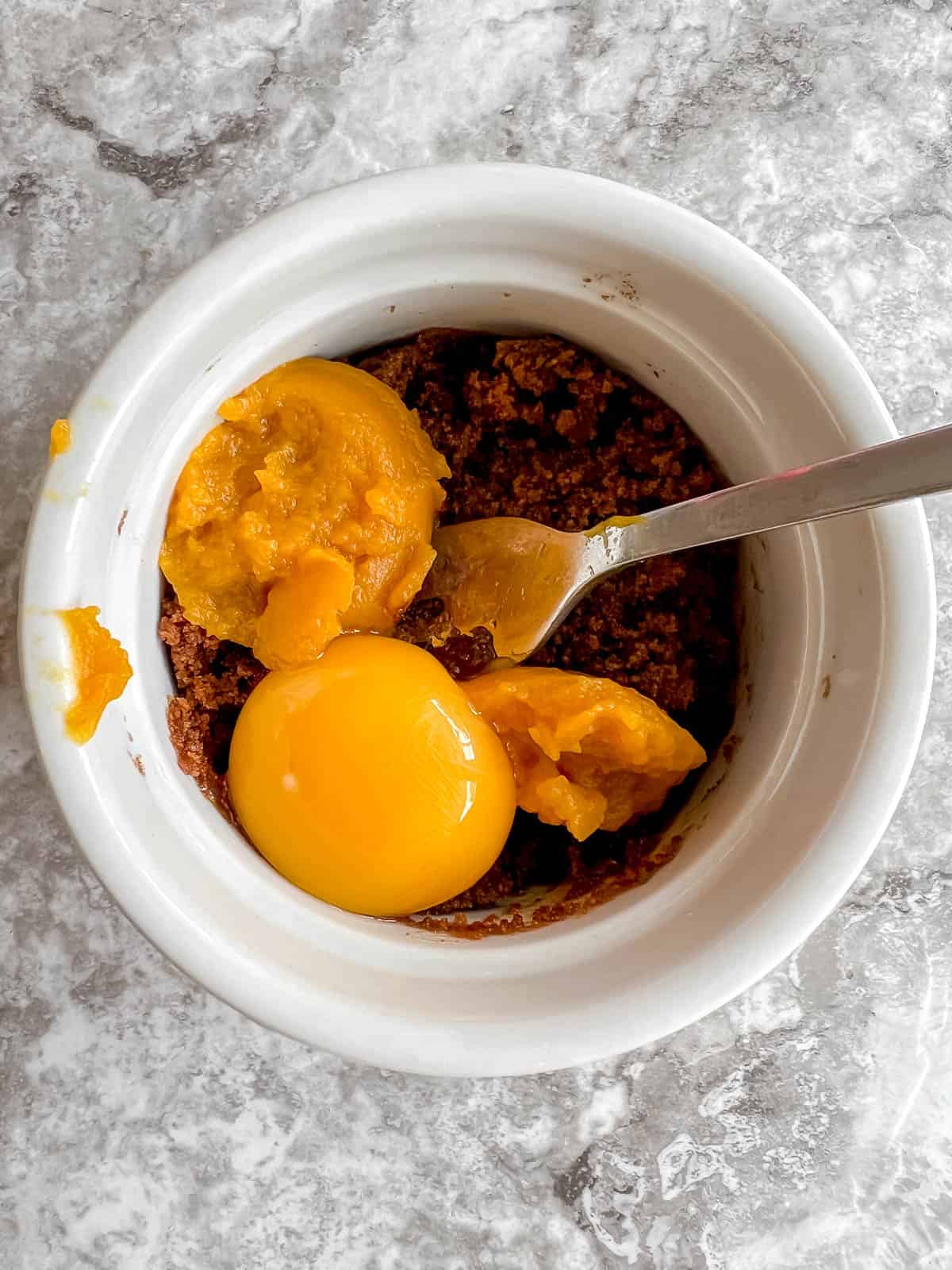 Pumpkin puree and egg yolk added to ramekin.